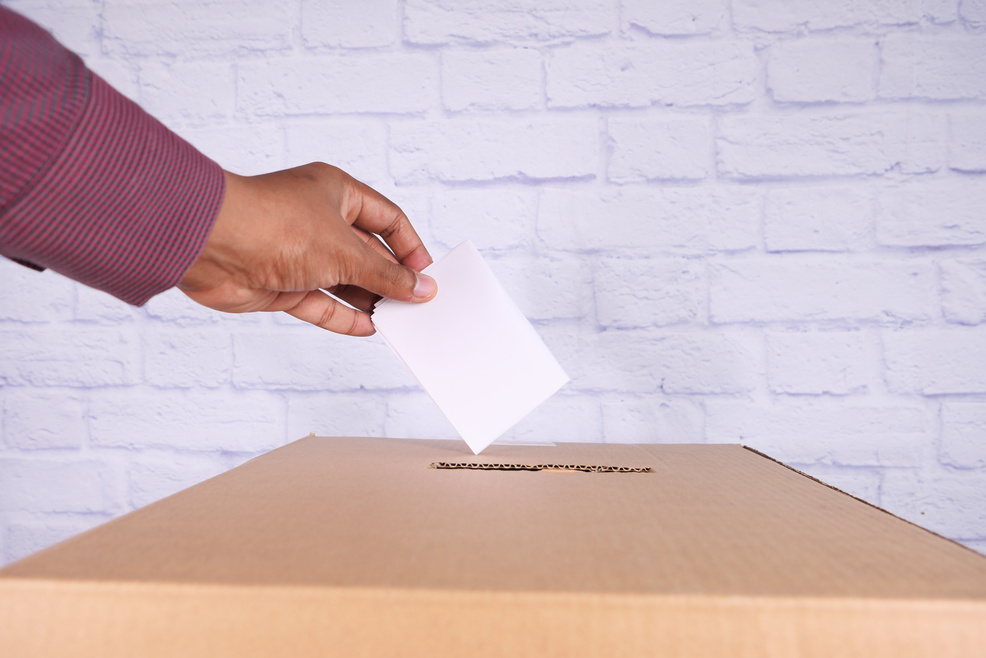 Close up of Man's Hand Putting Card in Box with Slot,